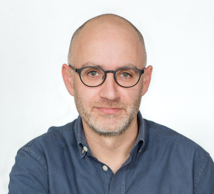 "Man in blue shirt and glasses looking seriously at the camera"