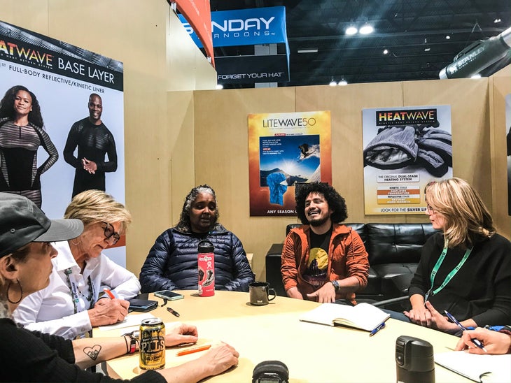 DEIStatement-2 Five people--three white women, one black woman, and a latino man-- sitting around a table in a meeting