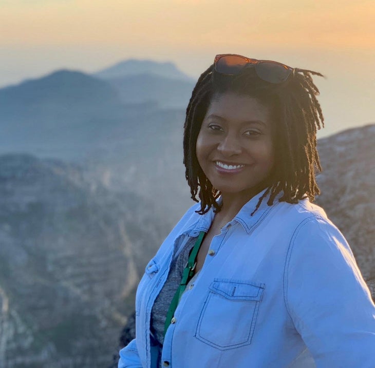 DenishaJenkins_cropped Denisha Jenkins smiles at the camera while the sun sets in the background over mountains.