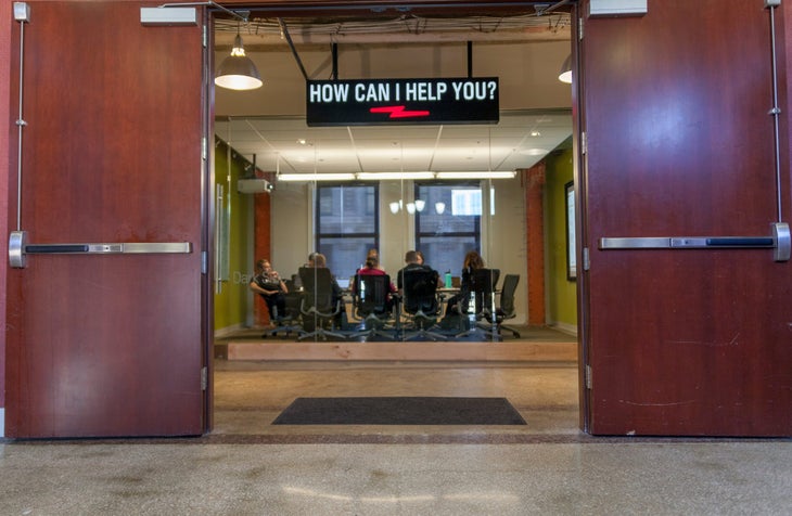 ExpertVoice office Open office doors looking in on a glass conference room where an Expert Voice team is meeting below a sign that reads \
