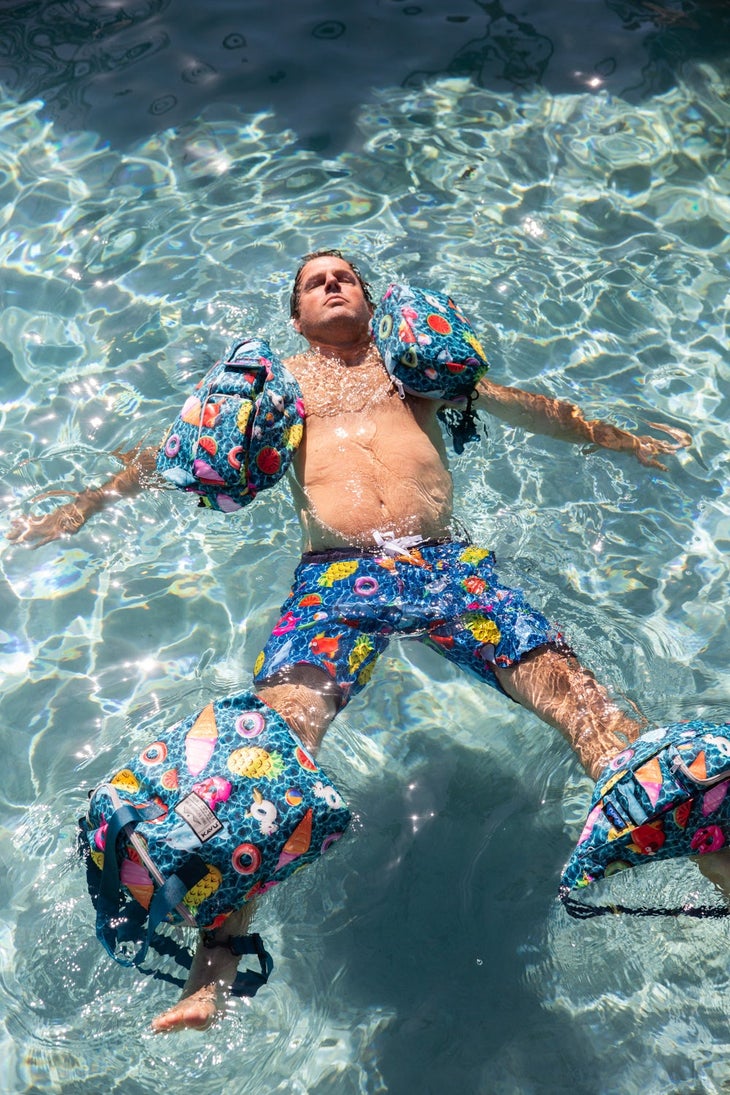 KAVU-S19-Lifestyle4 KAVU lifestyle clothing | Man floating in pool with colorful swim trunks and accessories