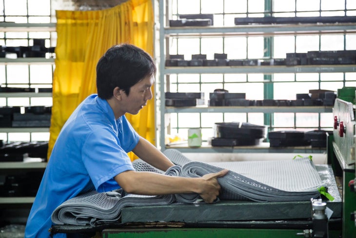 osprey factory Vietnam_holz-4036 A worker in a blue shirt moving fabric in Osprey's Vietnam backpack factory