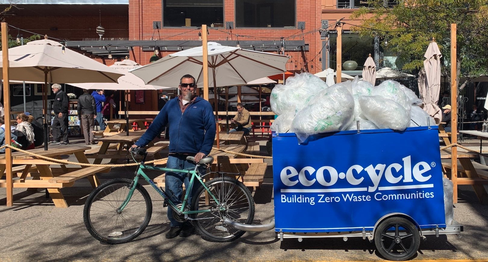 Man standing with bike bin full of plastic bags