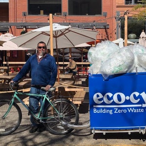 Man standing with bike bin full of plastic bags
