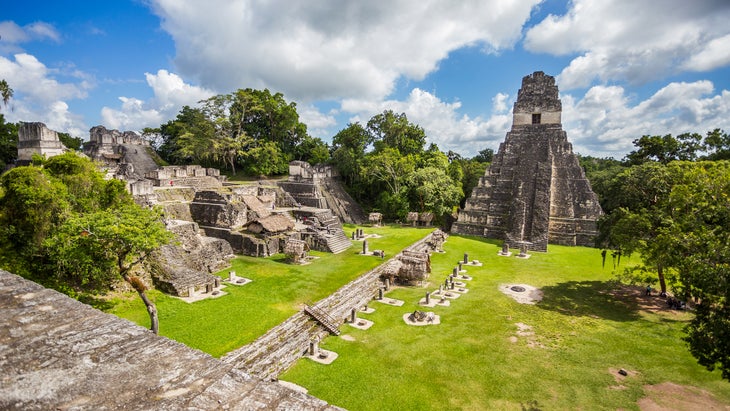 View of majestic mayan ruins with green grass and trees at Tikal National Park in Guatemala near the border of Belize.