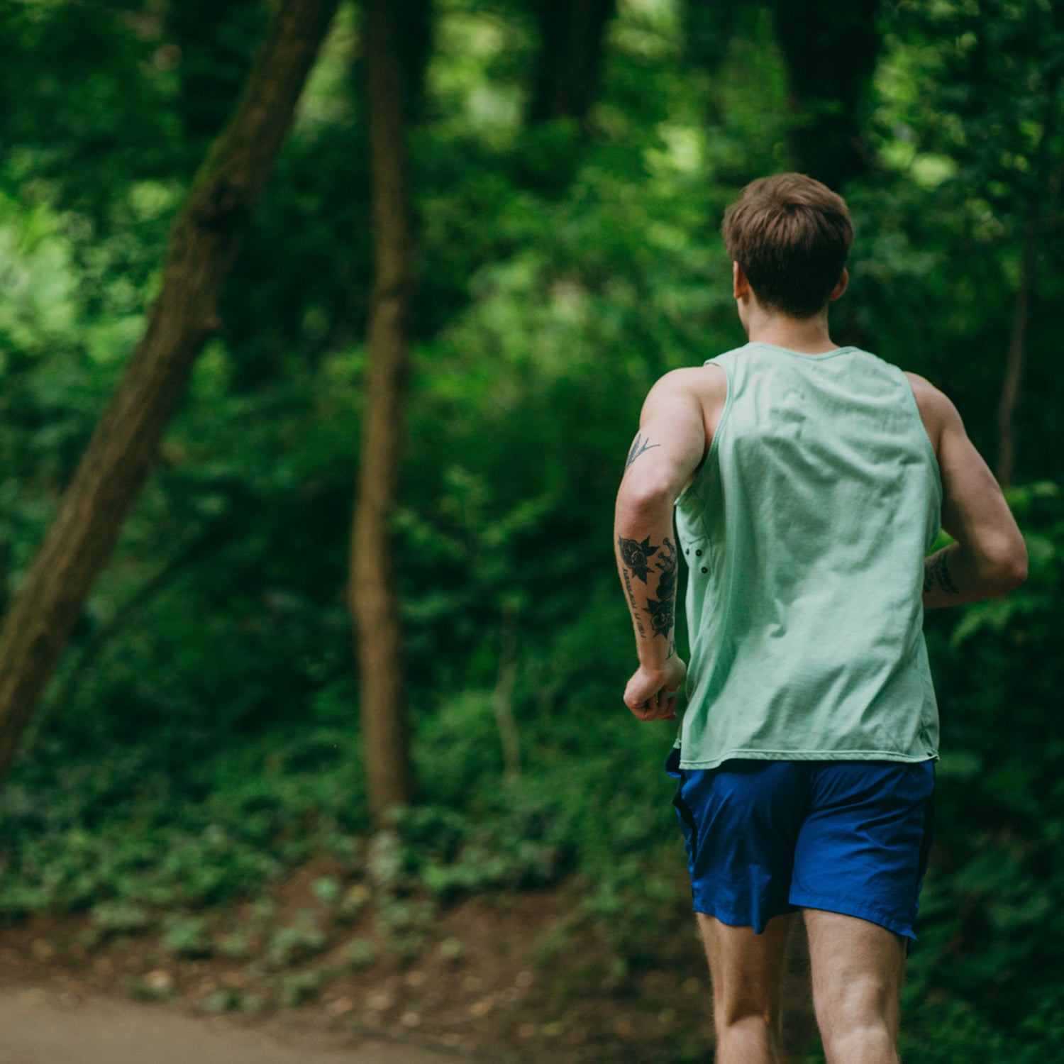 Runner training in the woods, from behind.