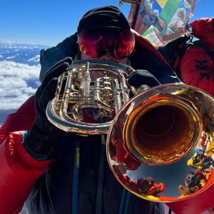 A climber plays a trumpet atop Mount Everest.
