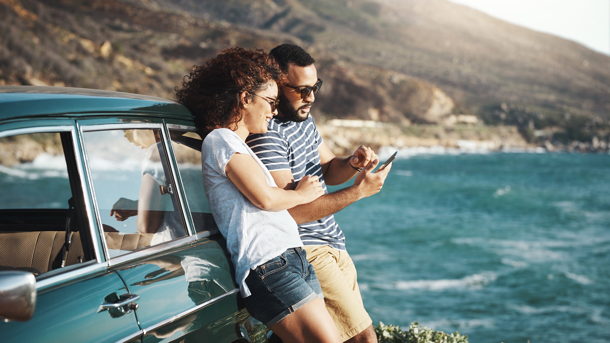Shot of a young couple using a mobile phone on a road trip
