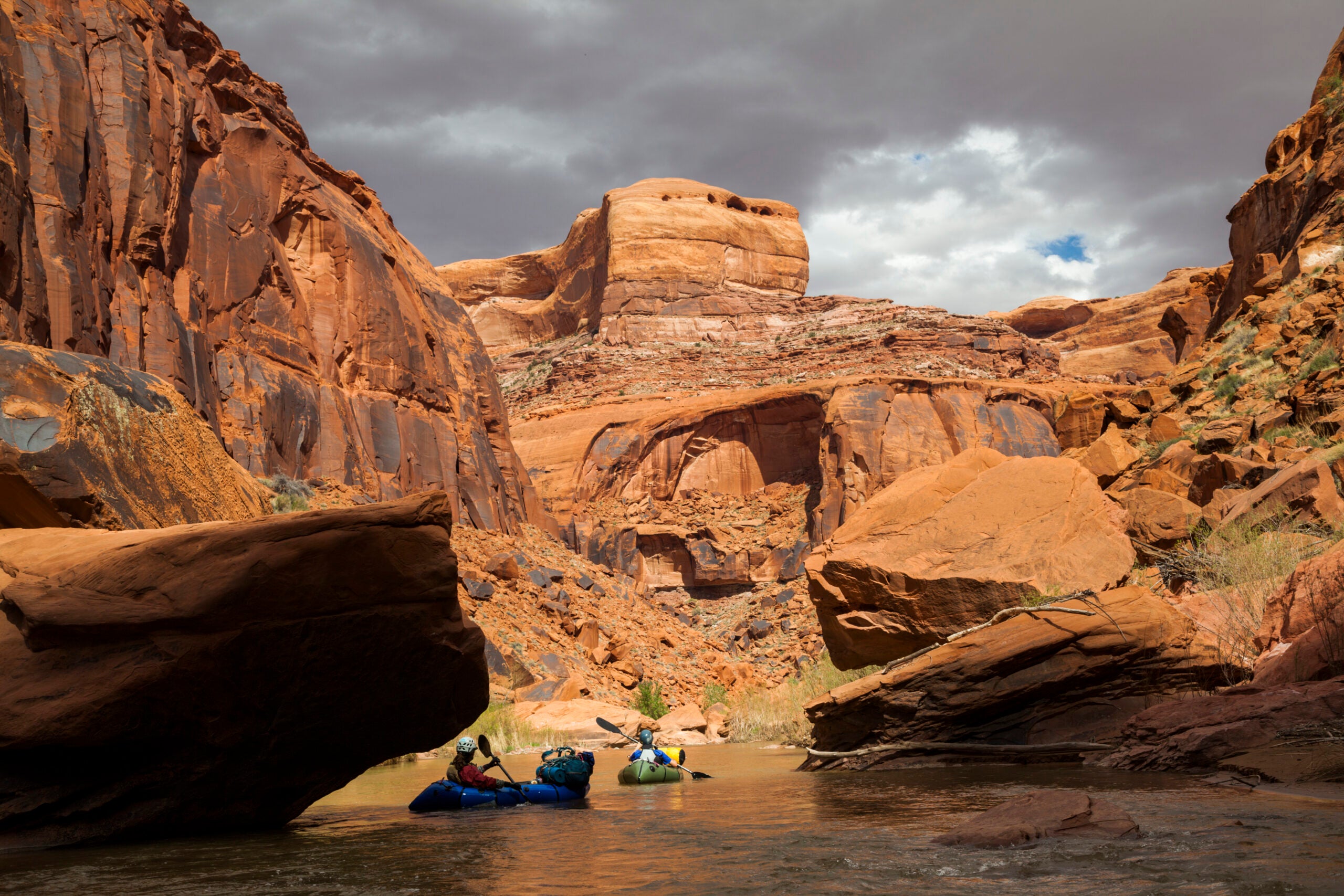 Packrafters paddle the Escalante River in Utah, through a sandstone canyon.