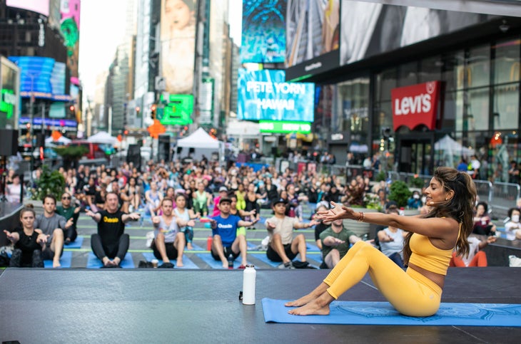 Hundreds of people do yoga together in the middle of Times Square in New York City