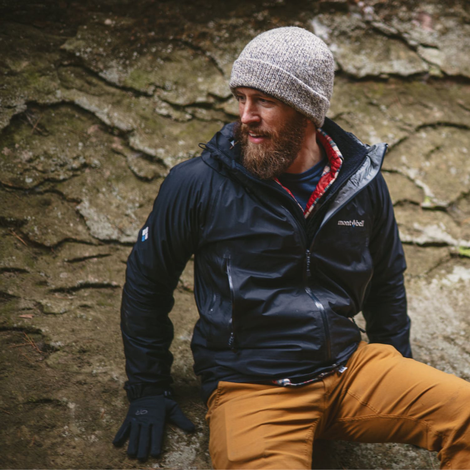Man in beanie and jacket sitting on a rock