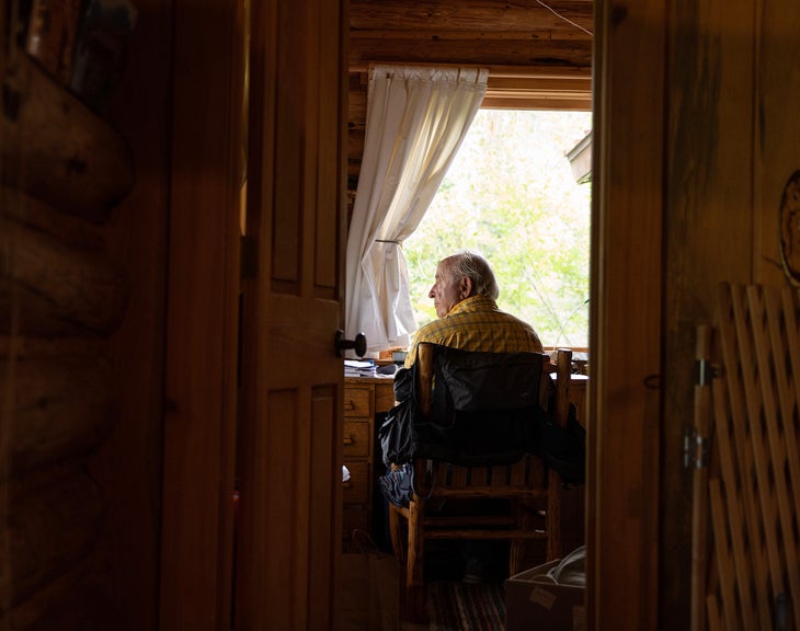 Man in yellow shirt sitting at a desk looking out the window