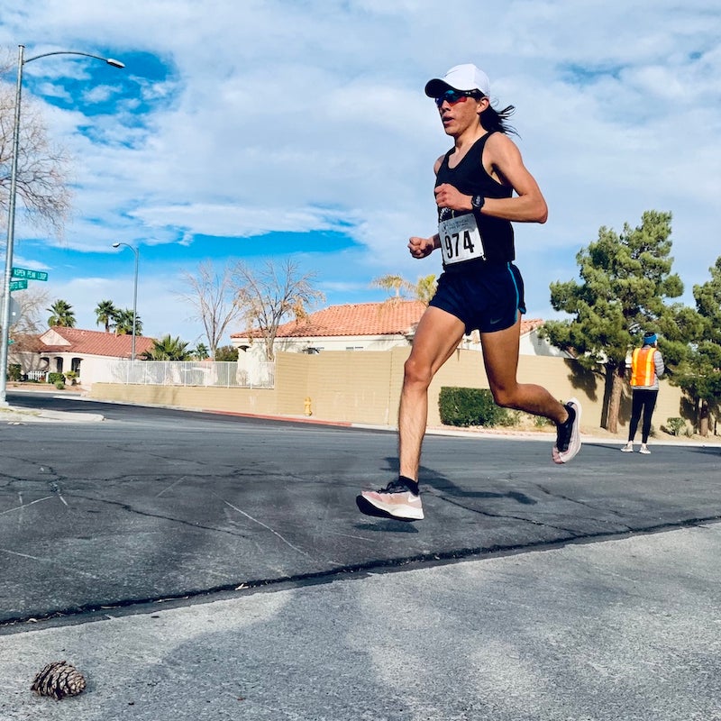 Indigenous runner on pavement with blue sky and wearing black