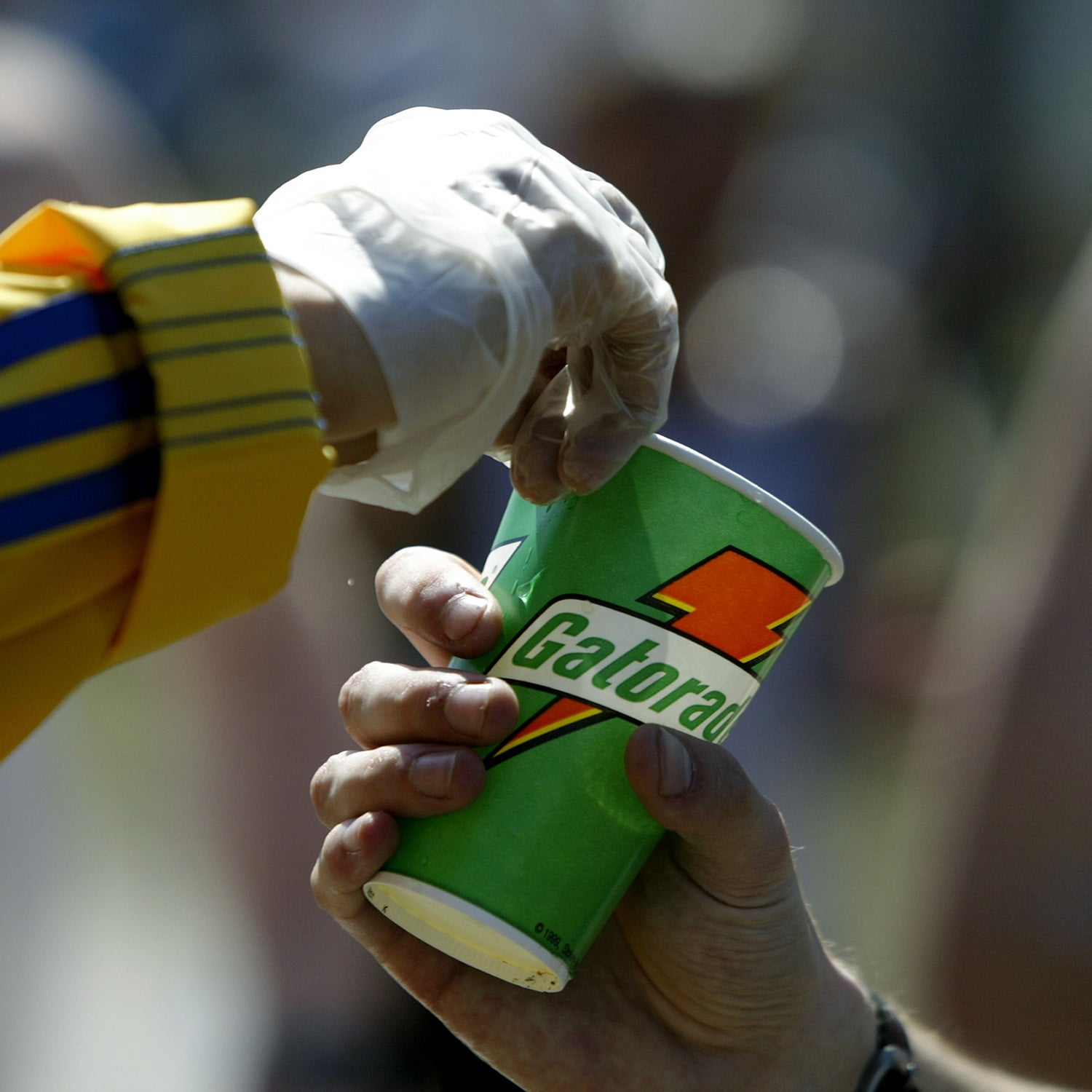 A detail shot of a volunteer as he hads a Gatorade refreshment cup to a runner as he passes through a water station in the town of Natick during the Boston marathon