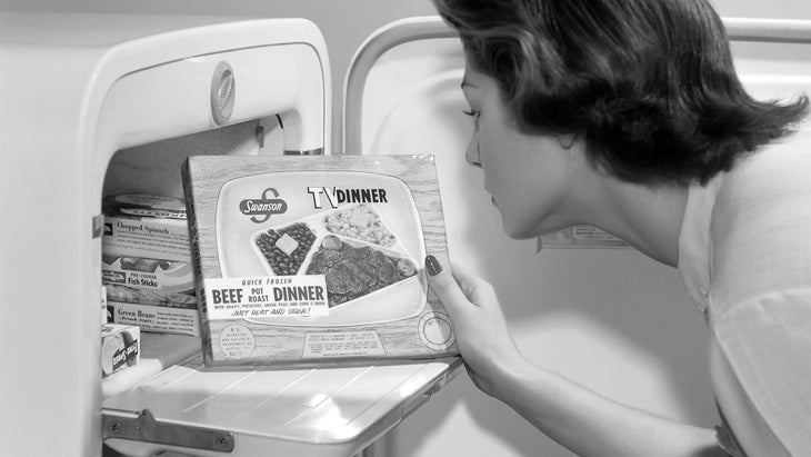 Vintage black and white photo of woman watching tv dinner box