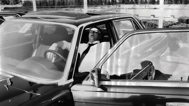 Vintage black and white photo of man sleeping in car