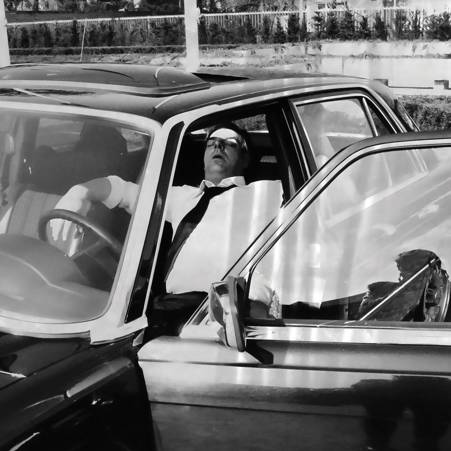 Vintage black and white photo of a man sleeping in a car