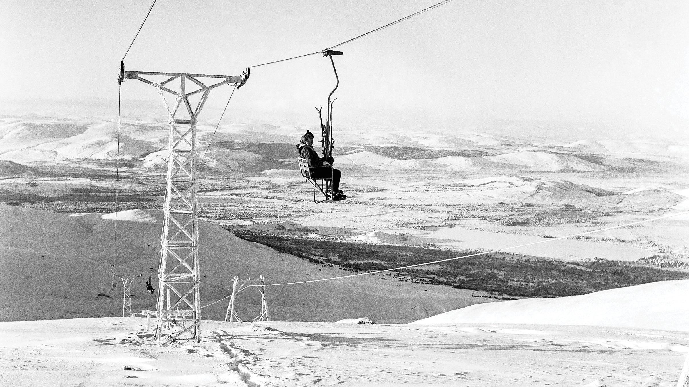 Black and white image of a single person alone on a chairlift