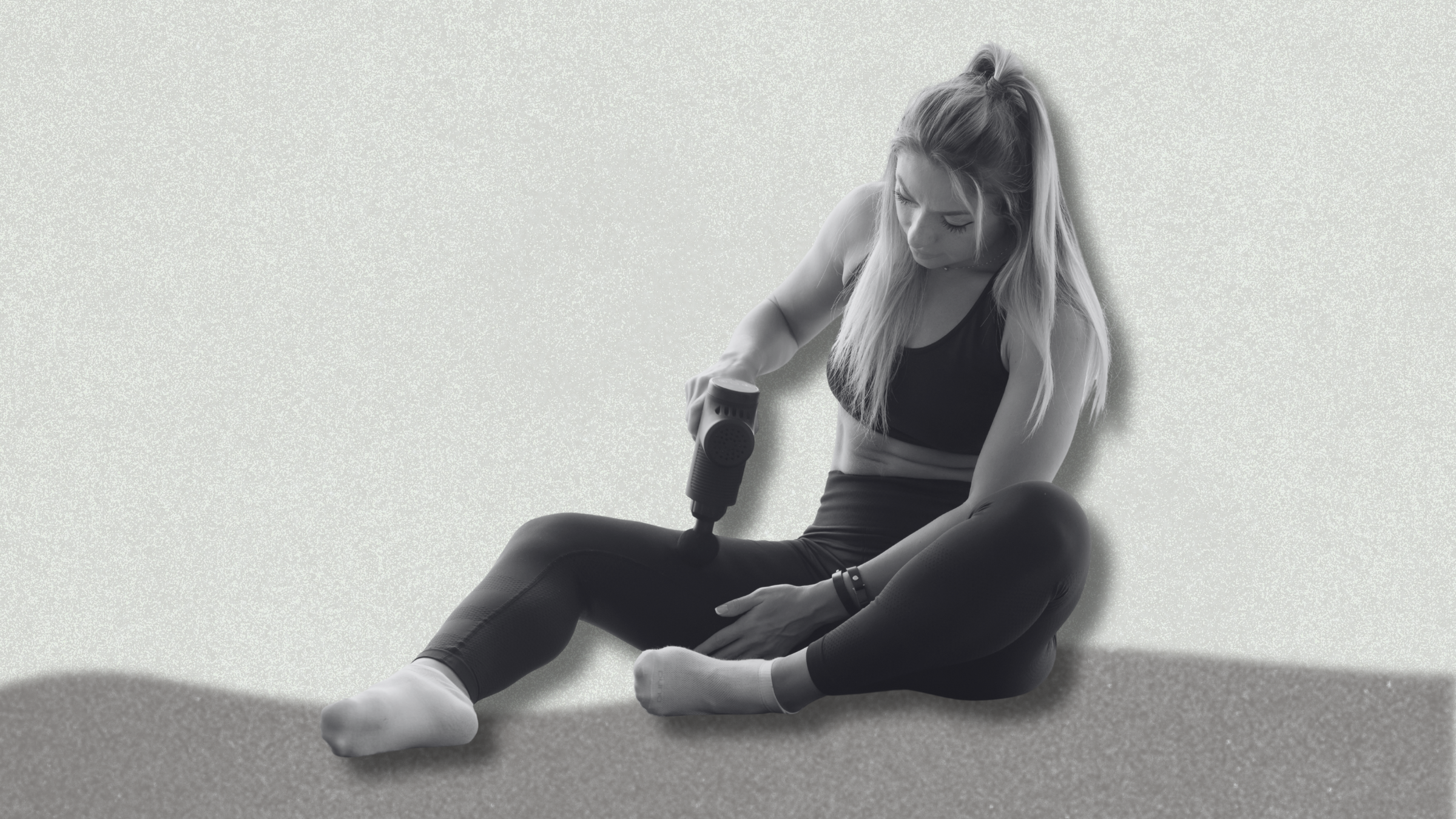 a person using a massage gun on a grey background