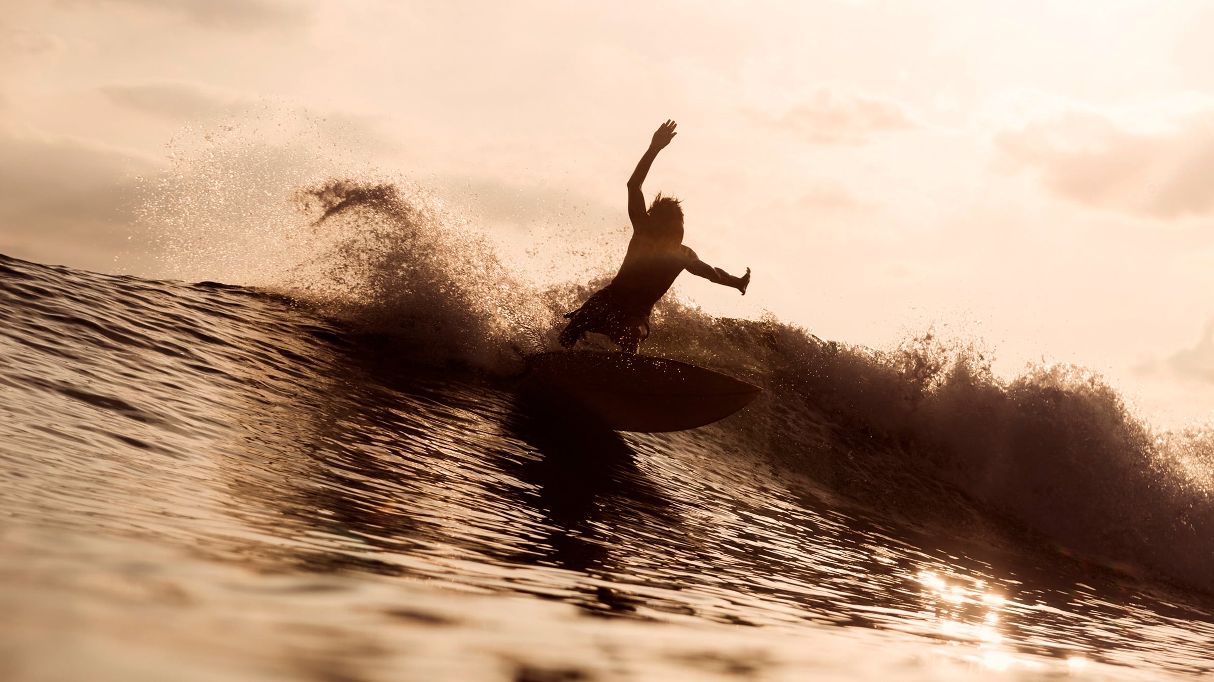 A surfer riding at sunset