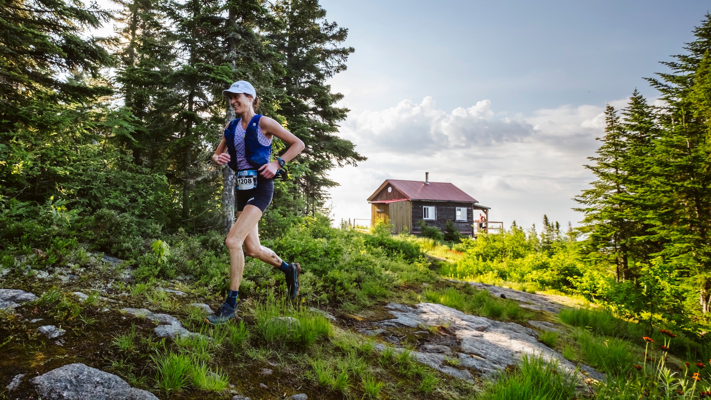 a women runs in a forest of green with a hut in the background