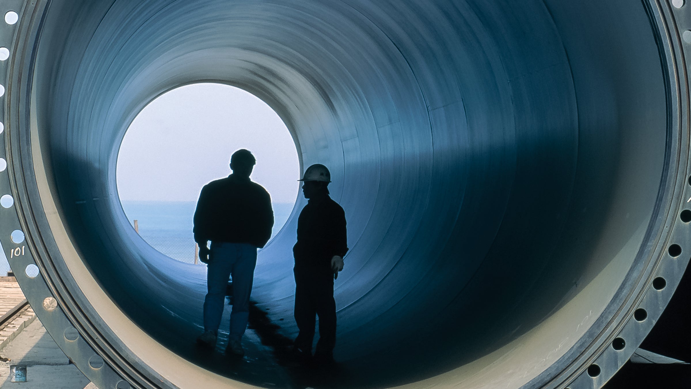 Site workers standing in a section of precast concrete pipe used for transporting water