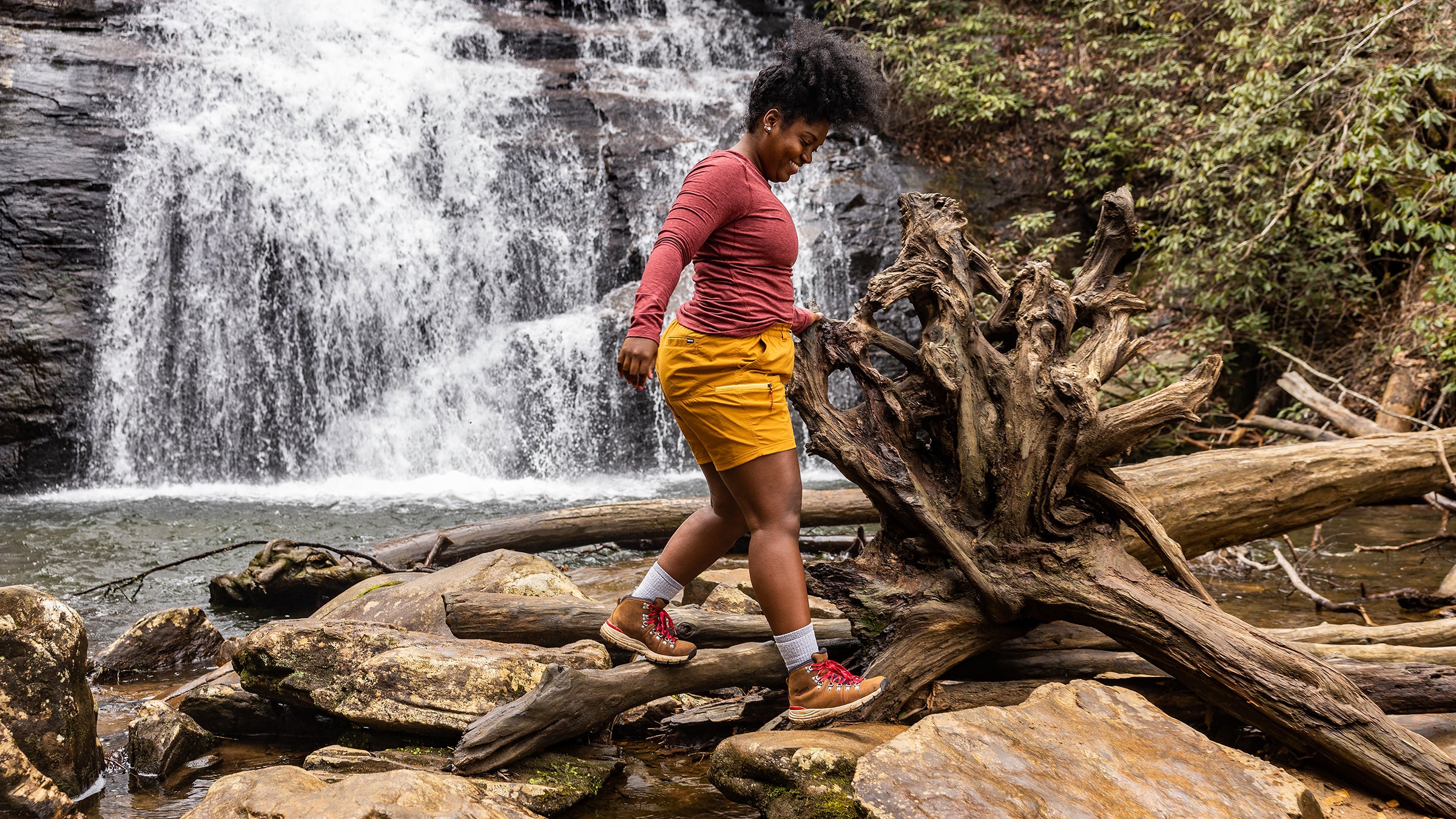 A hiker walks in front of a waterfall.
