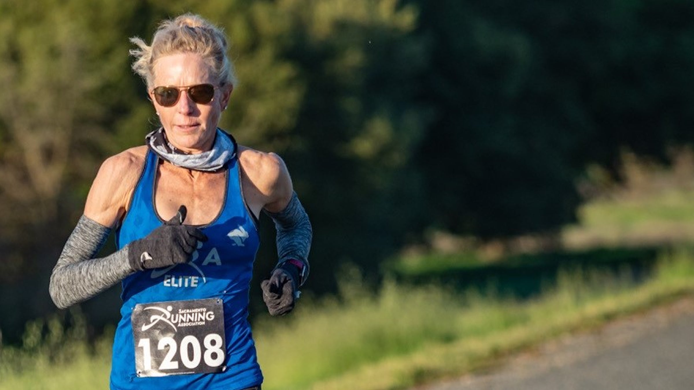 woman running a marathon in a blue singlet and arm sleeves