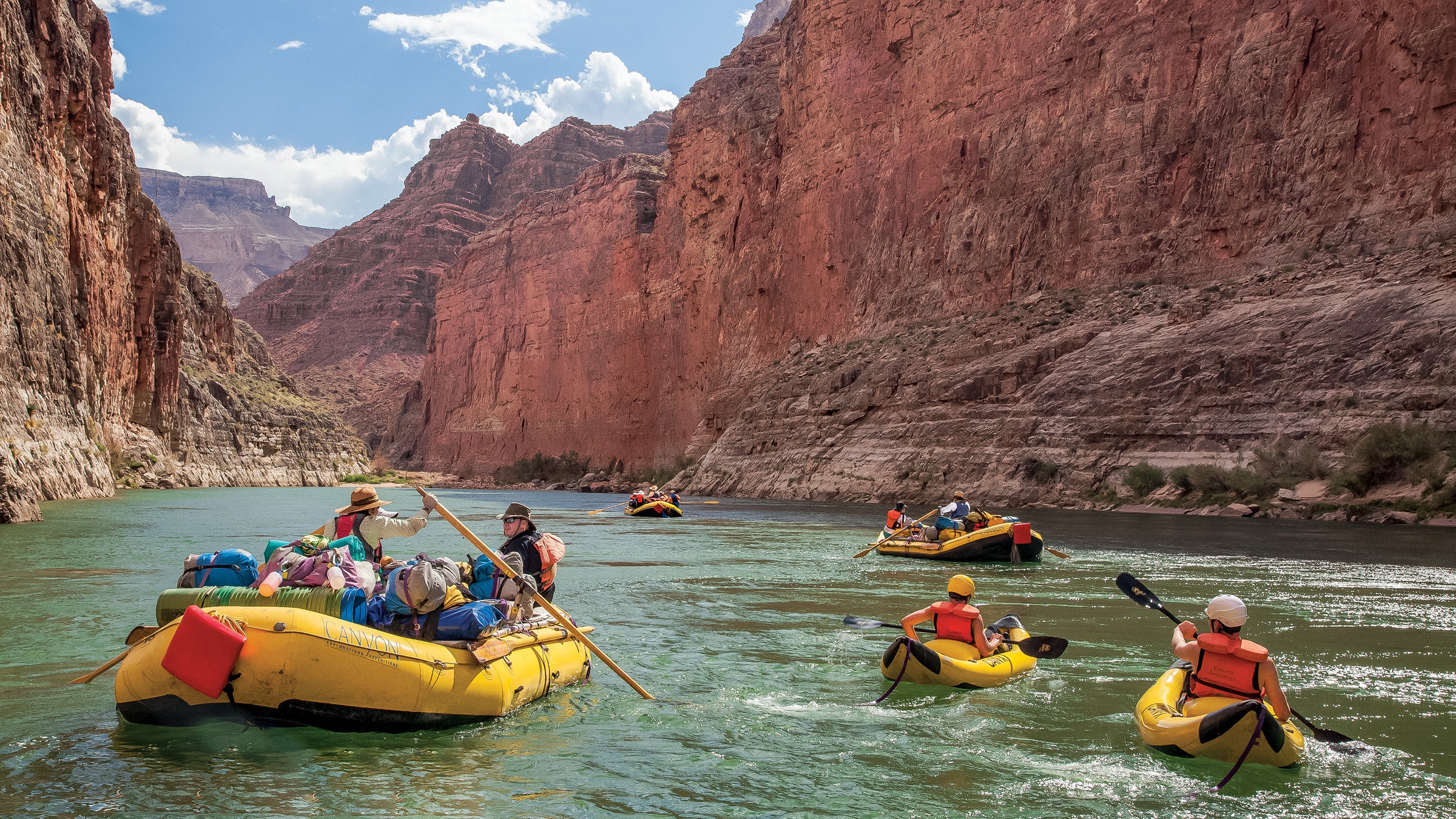 United States, Arizona, Grand Canyon National Park, whitewater rafts and kayaks below steep canyon walls on Colorado River.
