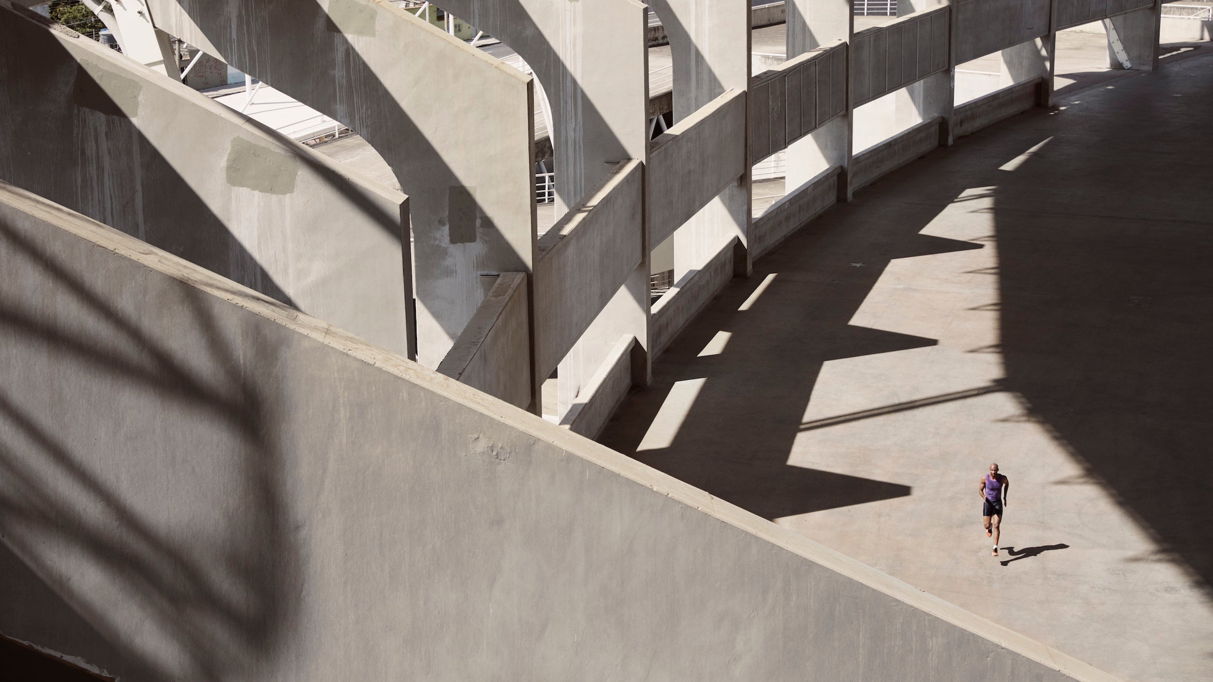 Long shot of a male athlete as he runs through a concrete stadium