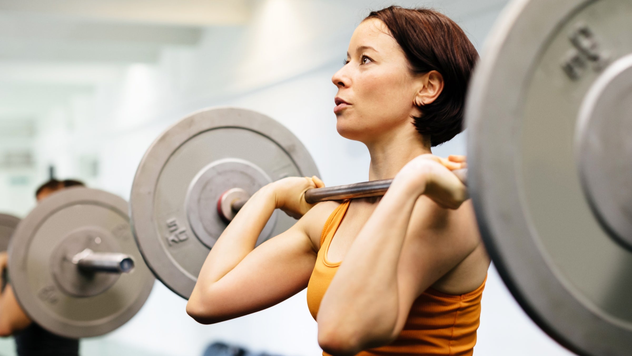 Young female athlete holding a heavy weight while practicing weightlifting in a gym.