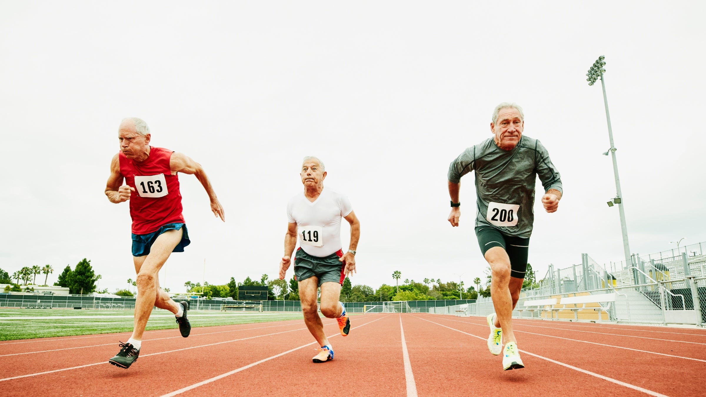 Three older men running a race on a track