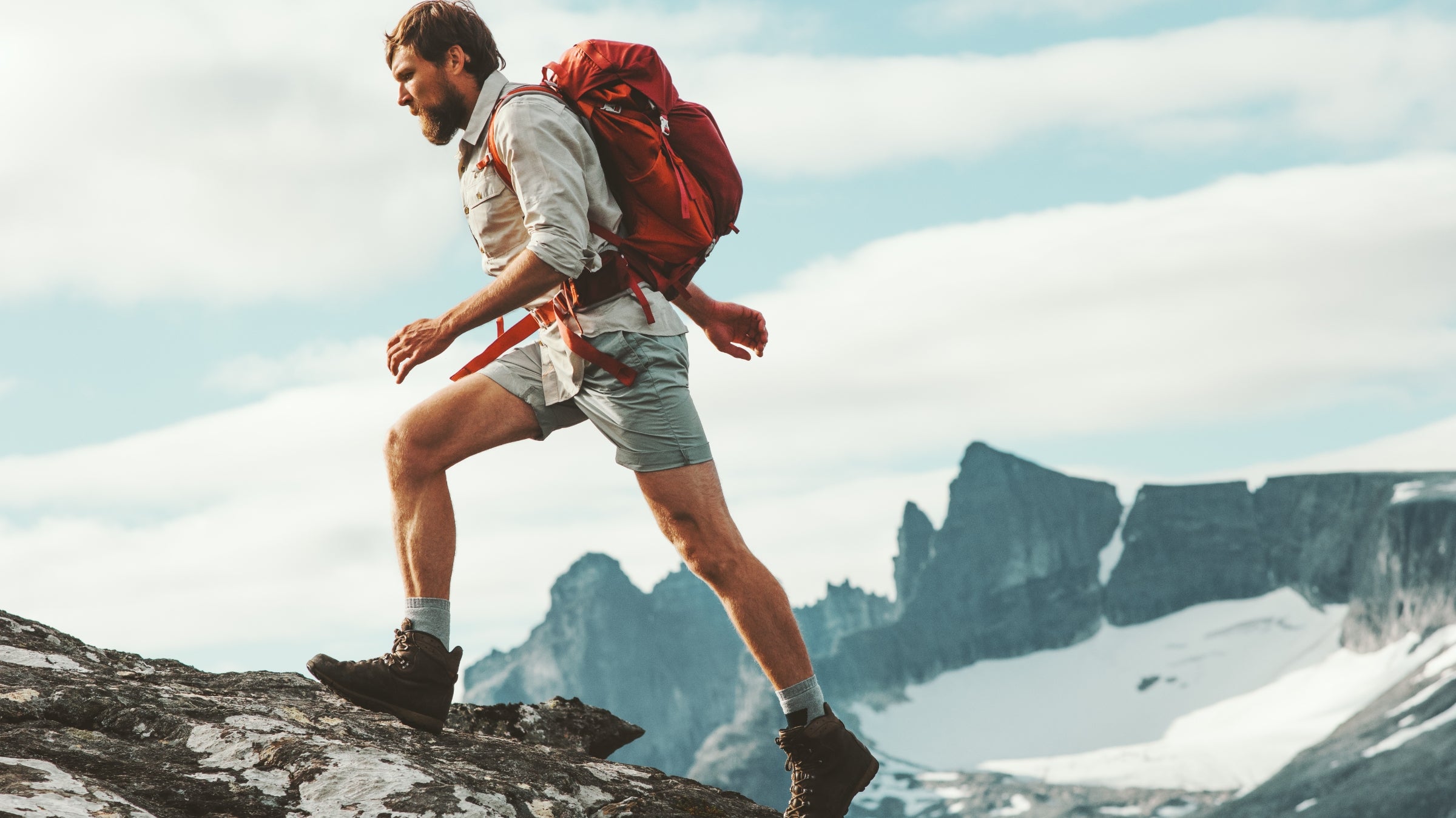 Man rucking in mountains with weighted backpack.