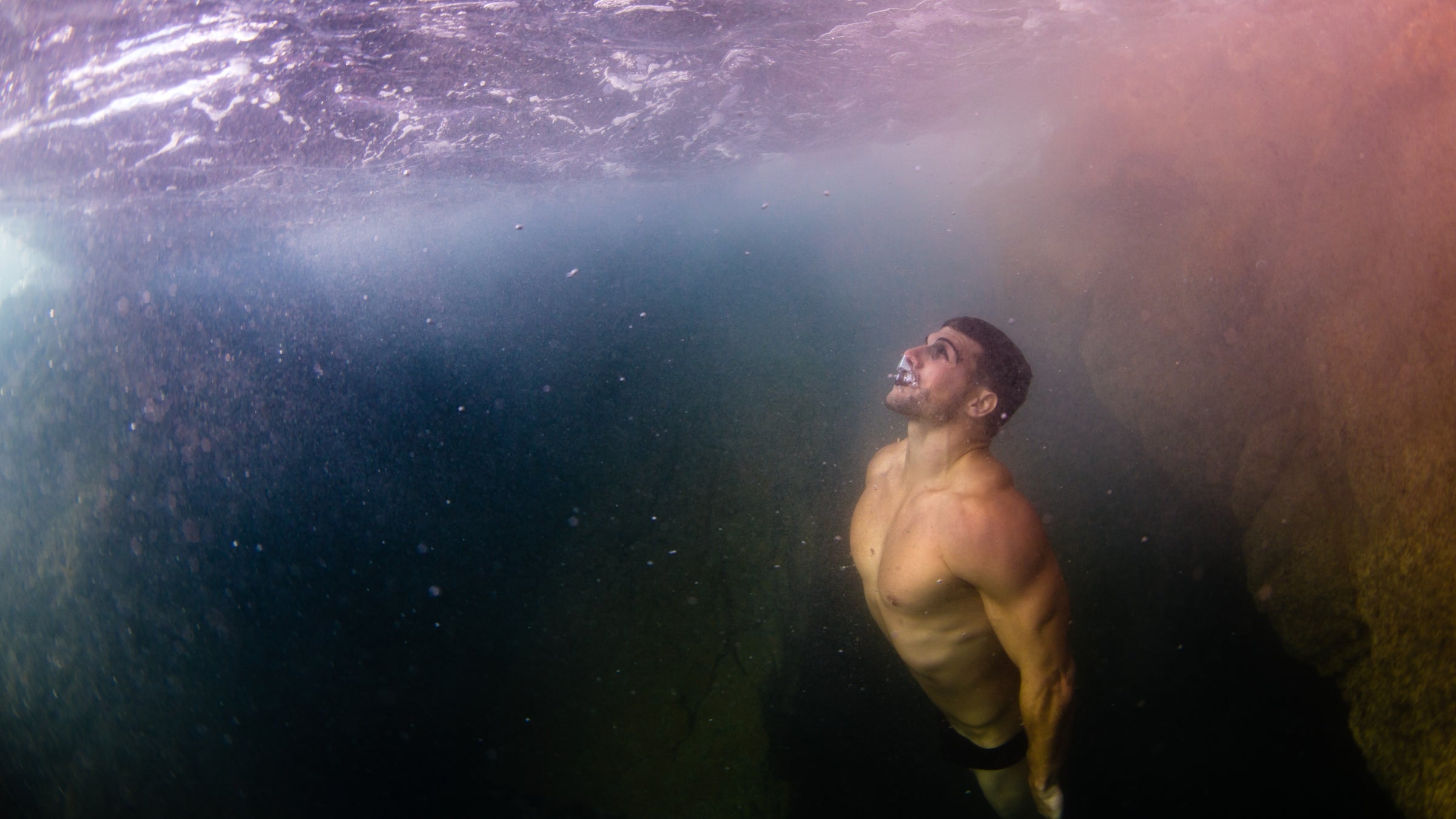 A white male diver swims to the surface after a breath hold