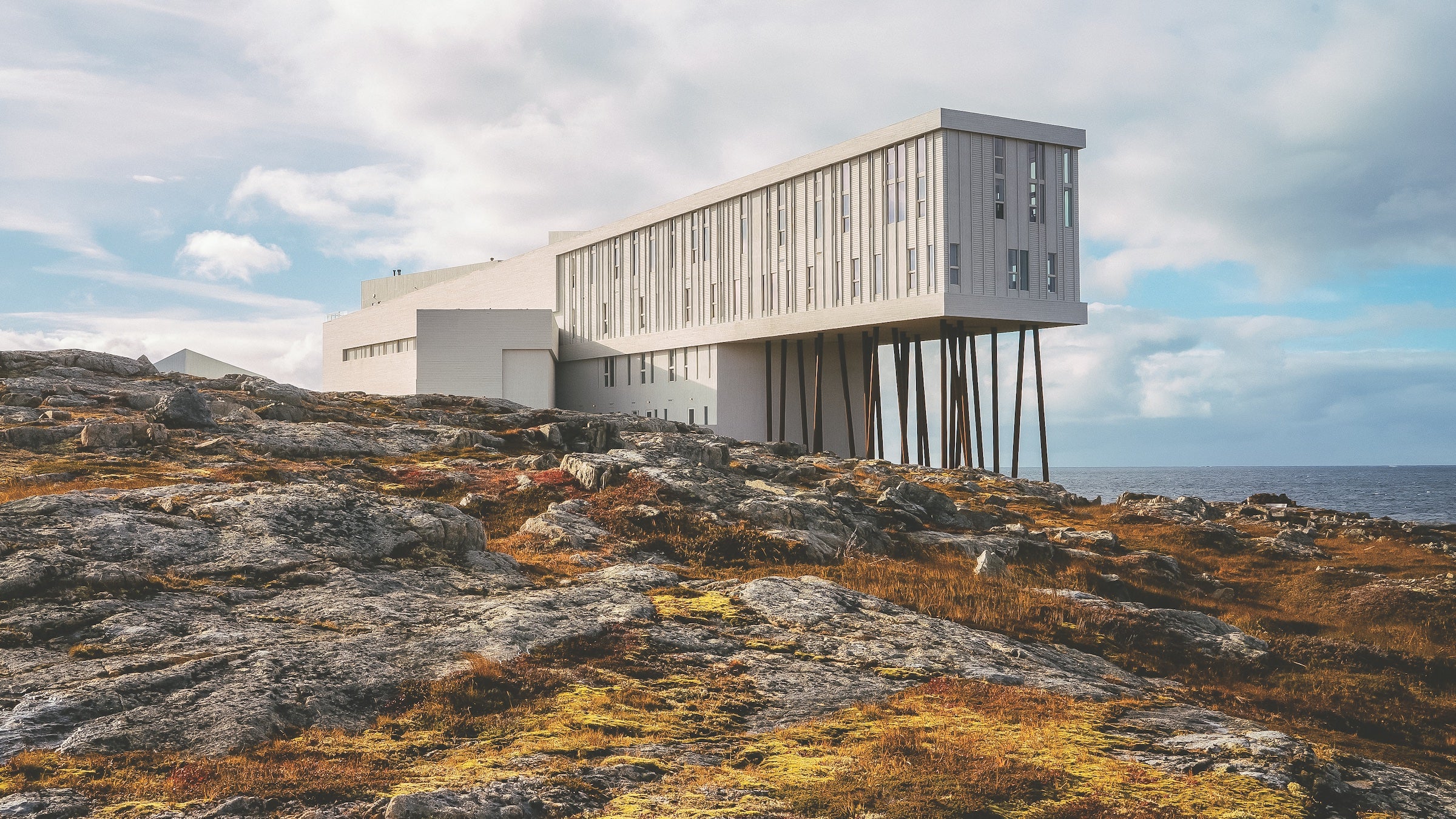 white building jutting over rocks