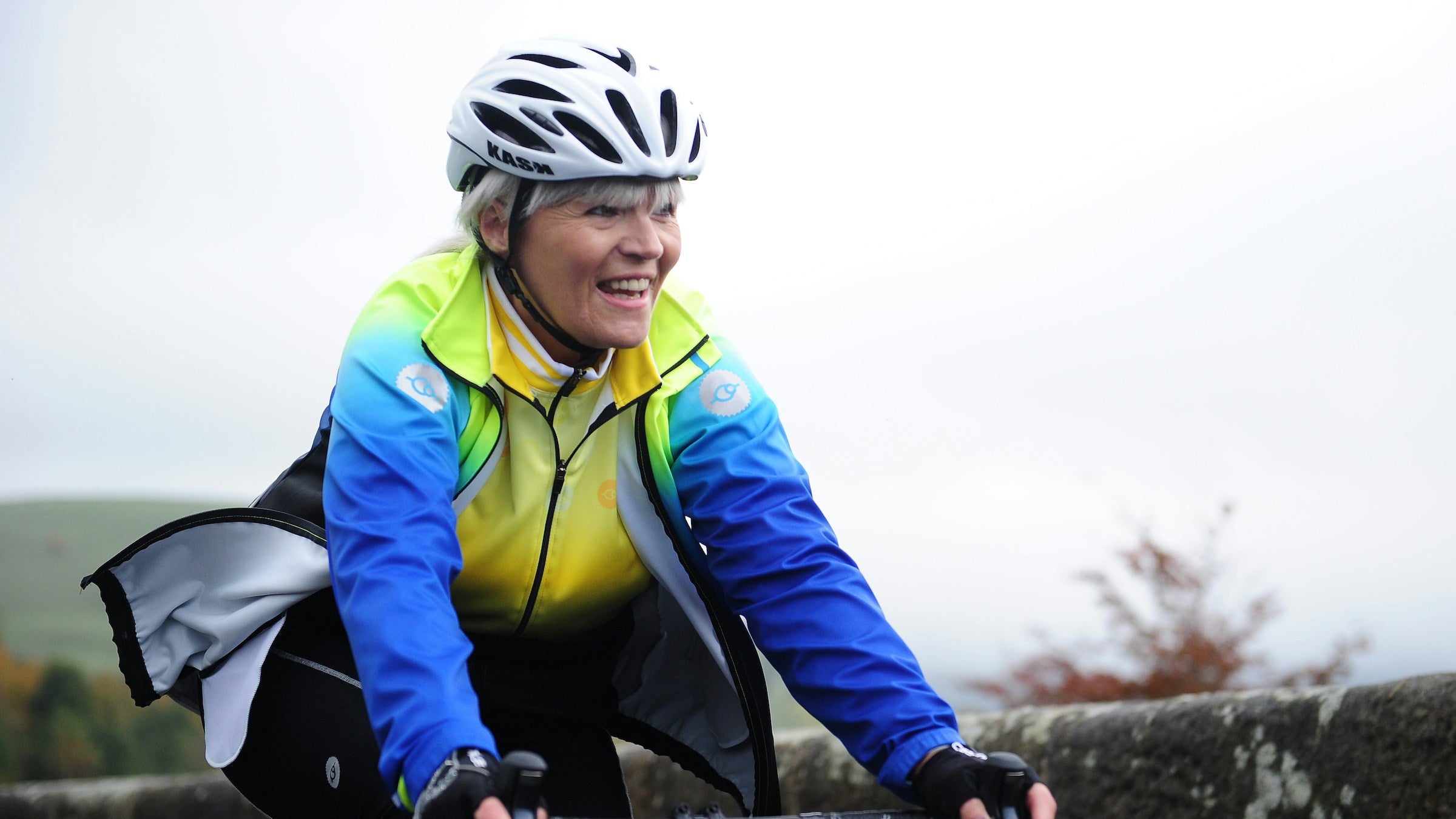 An aging woman smiling on a bicycle