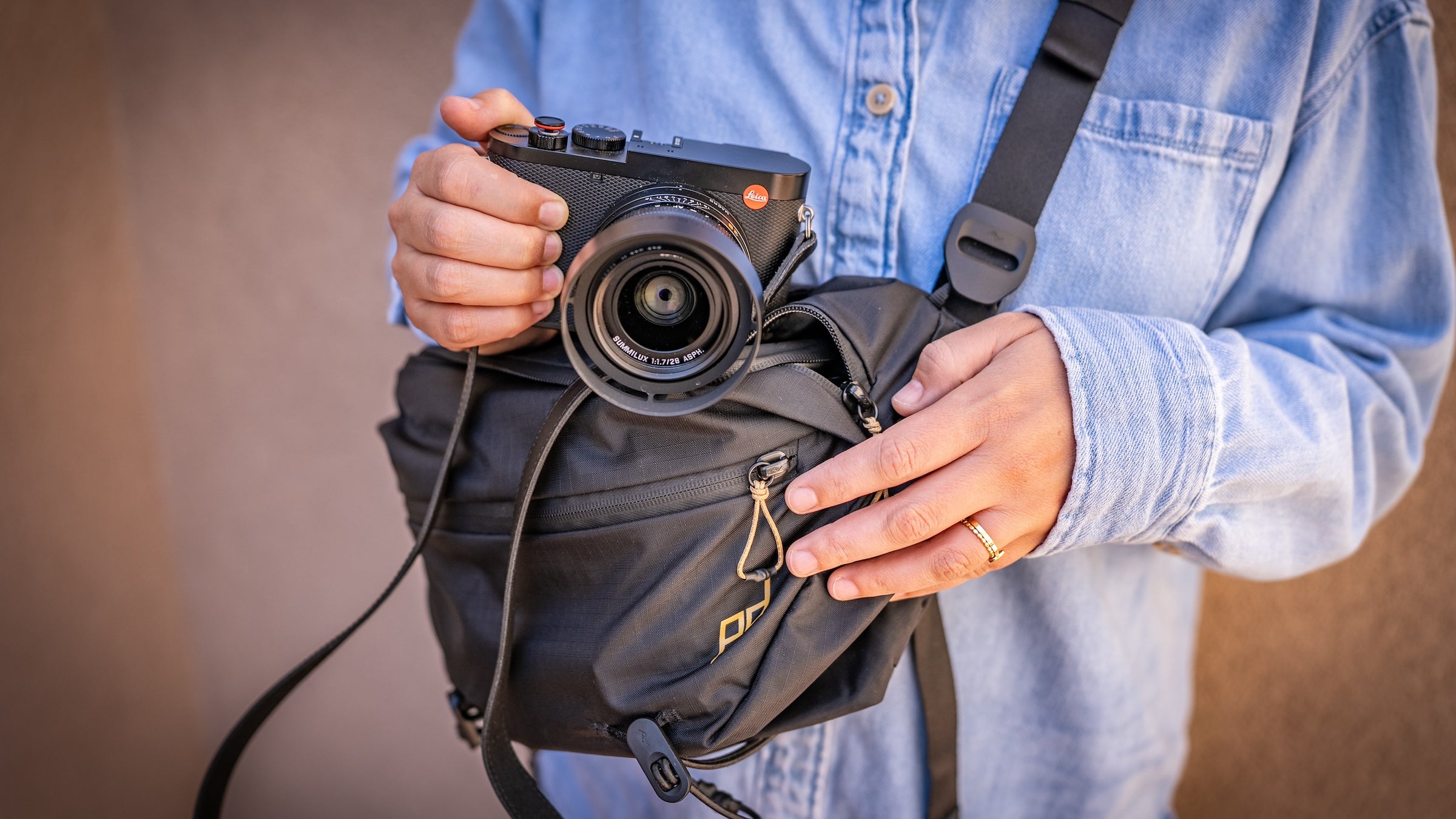 close-in photograph of a person in a chambray shirt holding one of the best camera bags