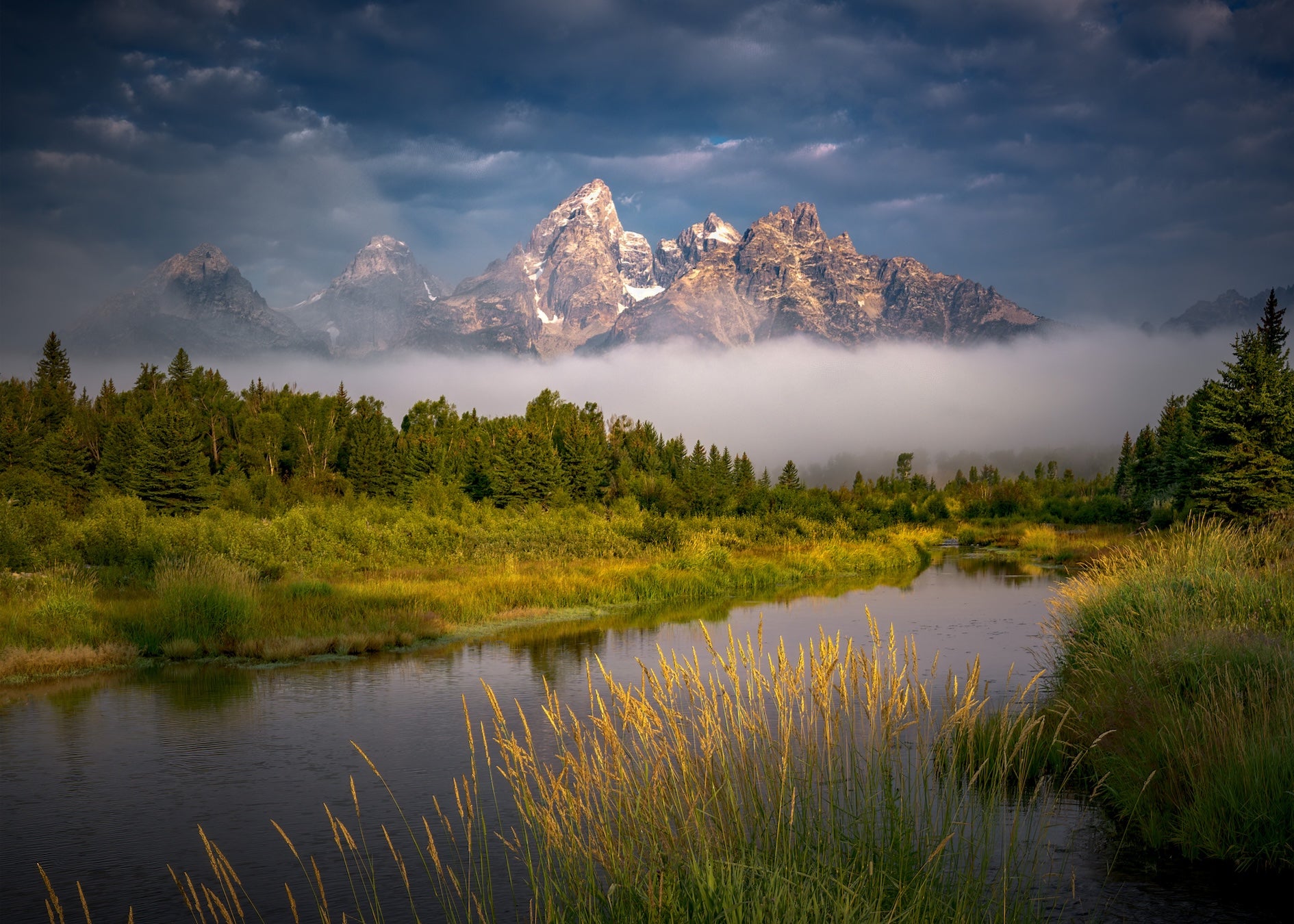 Stunning mountain scene in Grand Teton National Park with fog at the base of the mountains.