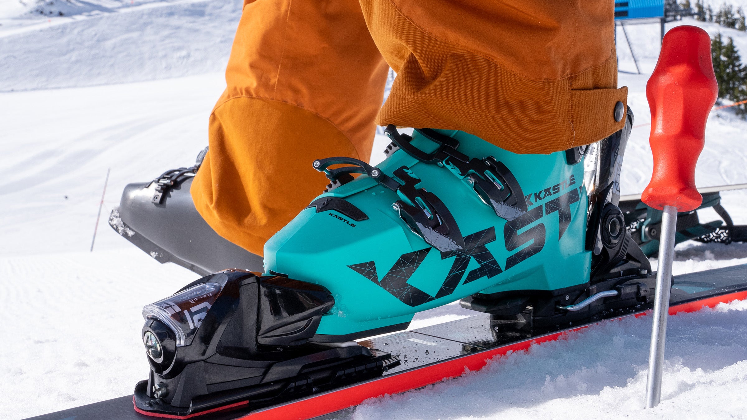 Closeup of turquoise Kastle ski boot clicked into ski on snow