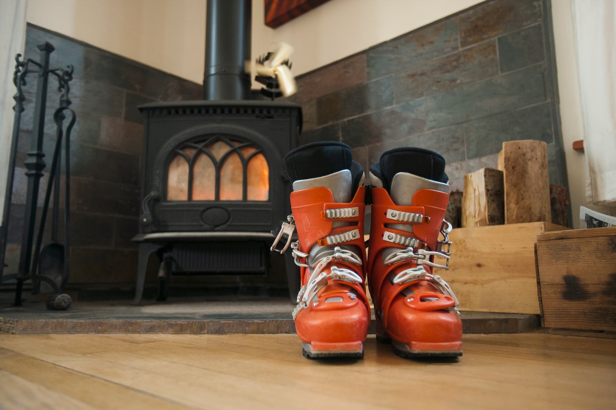 Orange ski boots with custom ski boot liner in front of wood burning stove