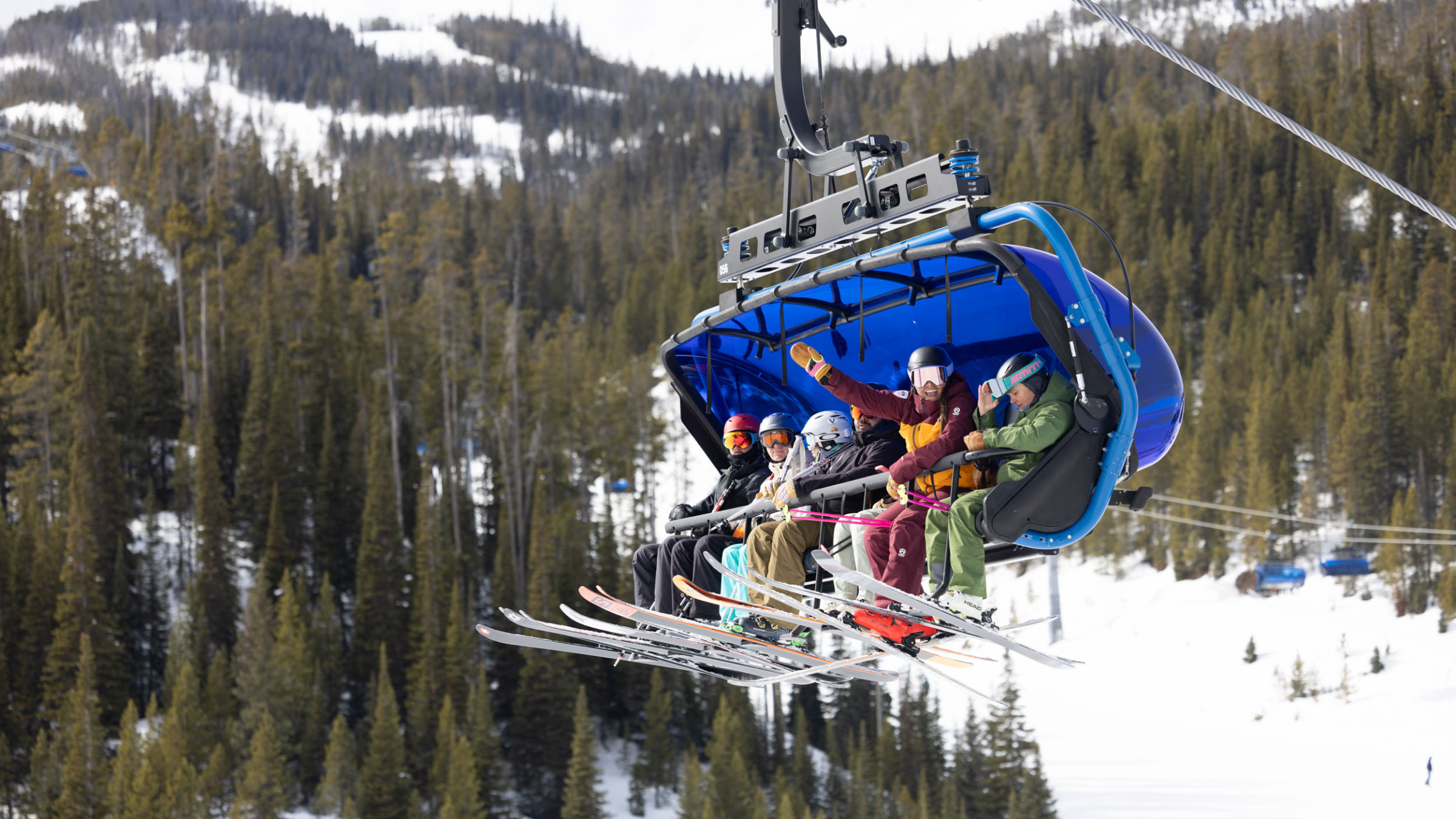 Skiers wearing the best budget ski jackets in colorful options riding a ski lift