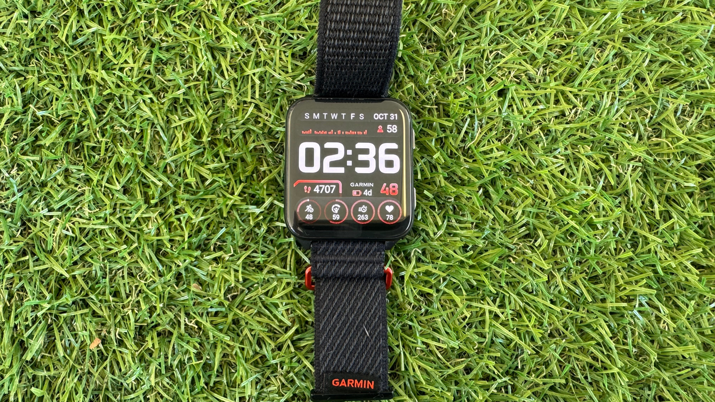 Garmin Venu X1 smart watch with black wrist band displayed on grassy background