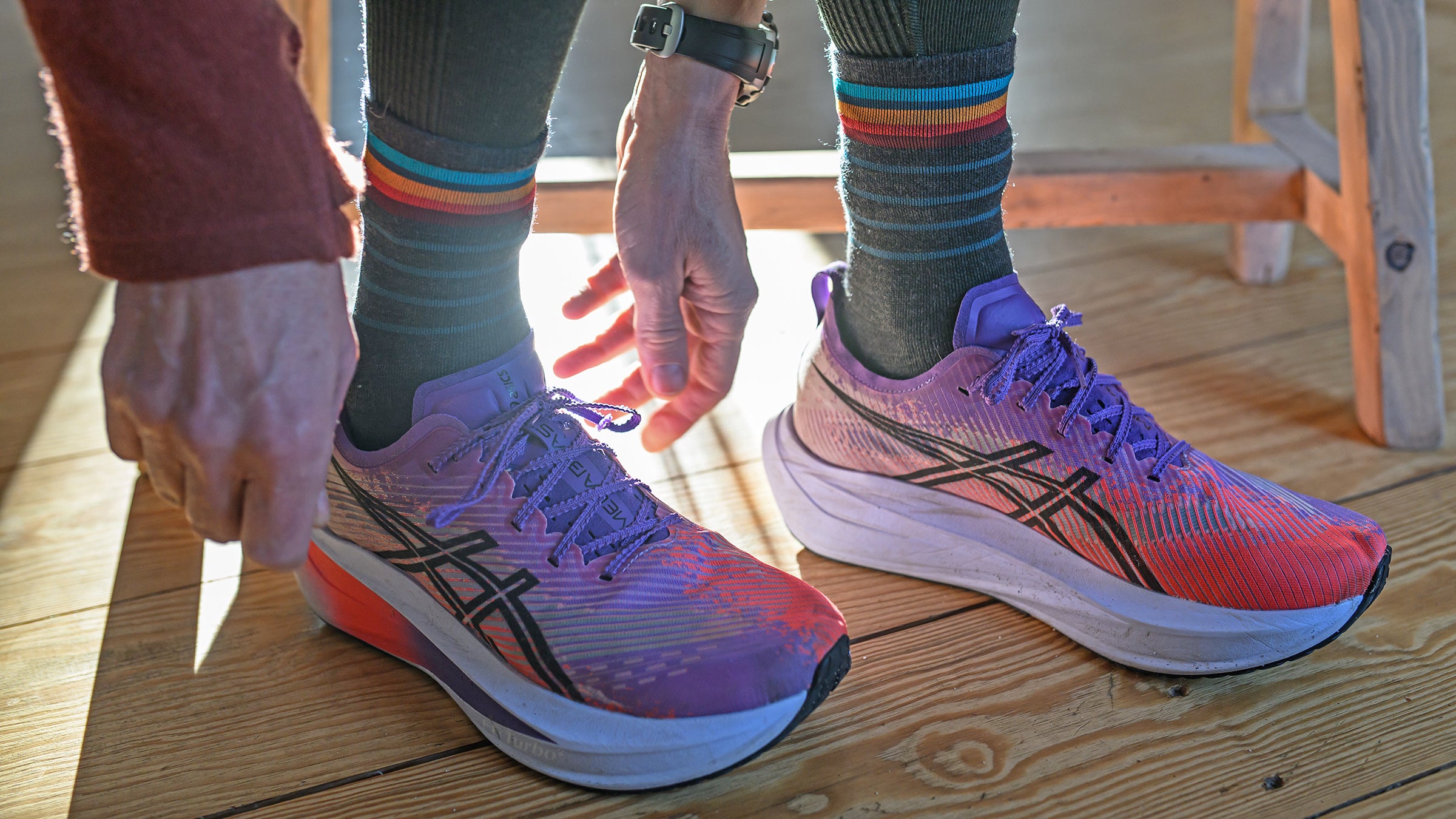 Runner lacing shoes over mid-height striped running socks.