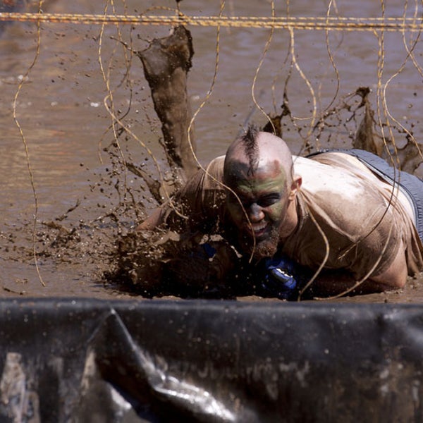 A participant crawls under live wires during a Tough Mudder event.