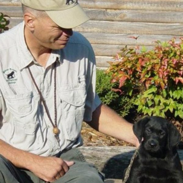 Mike Stewart with a young black Labrador Retriever.