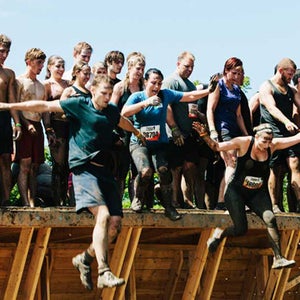 Participants leap off a platform in Tough Mudder's Walk the Plank obstacle.