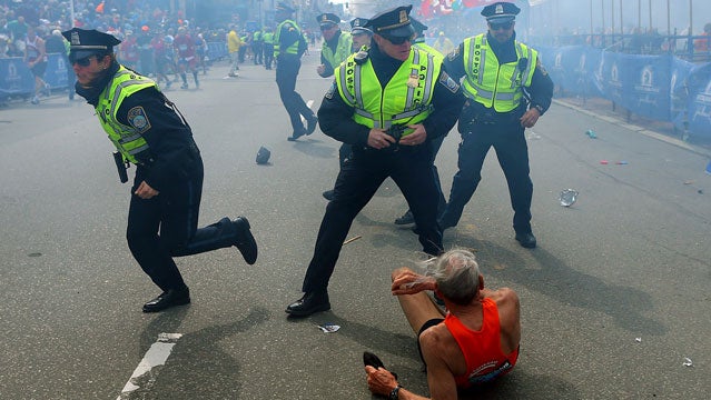 Police officers react to a second explosion at the finish line of the Boston Marathon in Boston, Monday, April 15, 2013. Two explosions shattered the euphoria of the Boston Marathon finish line on Monday, sending authorities out on the course to carry off the injured while the stragglers were rerouted away from the smoking site of the blasts. (AP Photo/The Boston Globe, John Tlumacki)