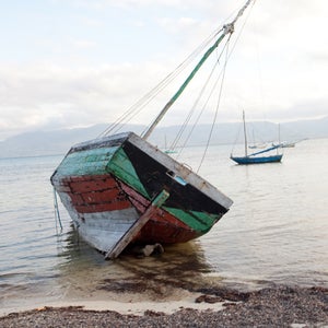 A young girl runs past boats on the beach.
