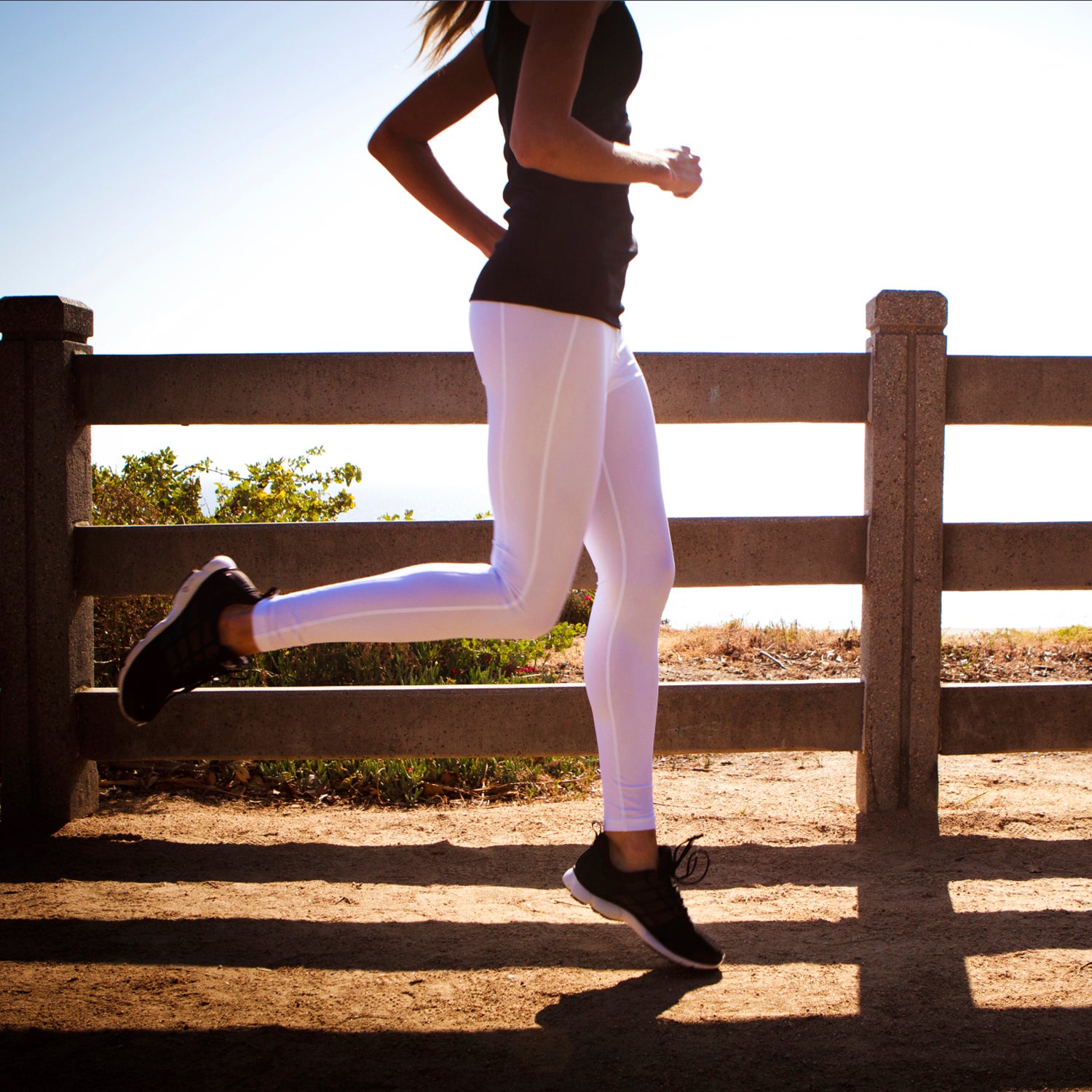 Young woman running & exercising on a park trail
