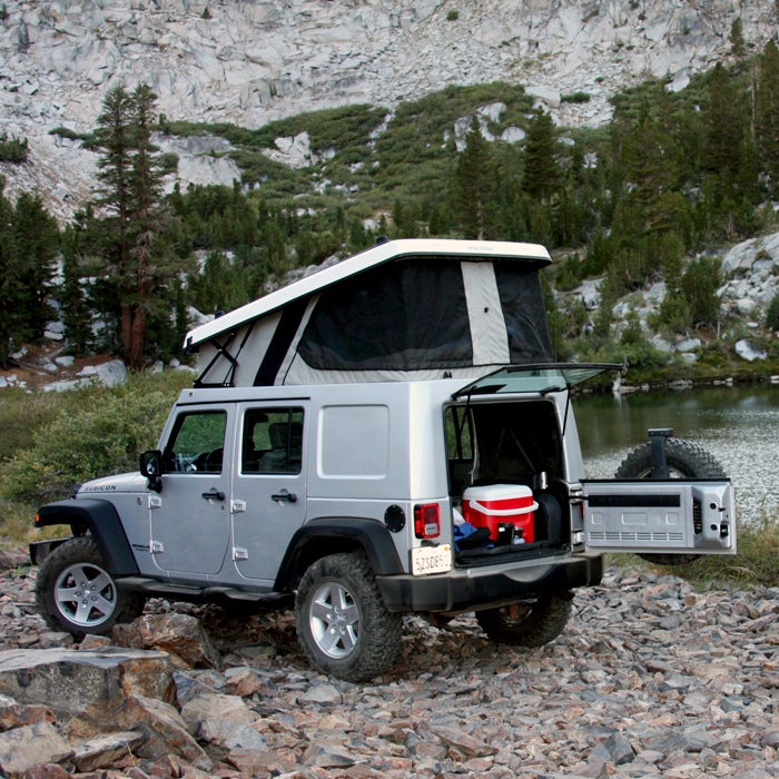 Ursa Minor gained fame with its E-camper Honda Element pop-up—a conversion that cost much less than other options on the market. When the car was discontinued, Ursa started making modern pop-tops for Jeep Wranglers (starting at $5,700).
The flatbed-camper design minimizes noise, maximizes fuel economy, and adds only about six inches to the Jeep’s height. When fully opened, the space is large enough to accommodate a seven-foot mattress, interior LED lighting, and zippered screen windows. You’ll be comfortable, no matter the campsite. A fold-over version holds four people.
